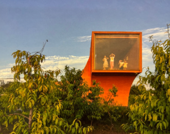 An image of people looking out of a window above trees.