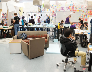 Inside of a classroom with students sitting and standing.