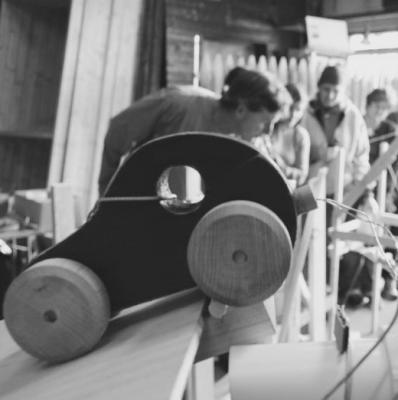 A wooden car sitting on the edge of a slanted wooden platform.