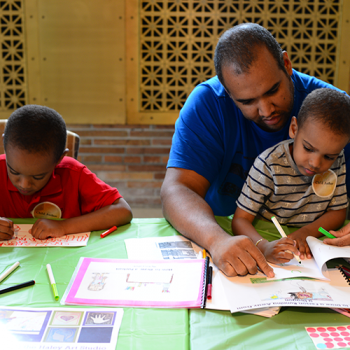 Adult helping children go through a workbook.