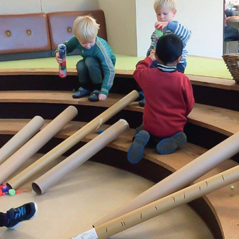 Children playing with cardboard tubes and small toys.