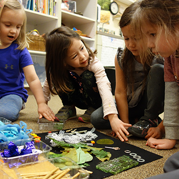 Young students creating a collage of artifacts on the floor.