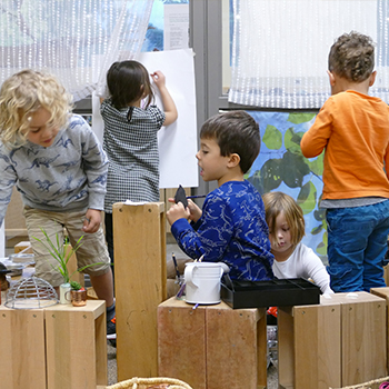 Students drawing and doing other activities around wooden benches.