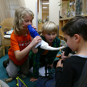 Students talking into paper cones and microphones.