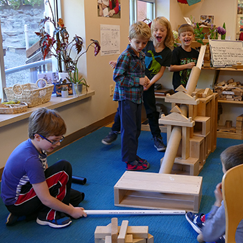 Students creating a tunnel with blocks, cylinders, and PVC pipes.