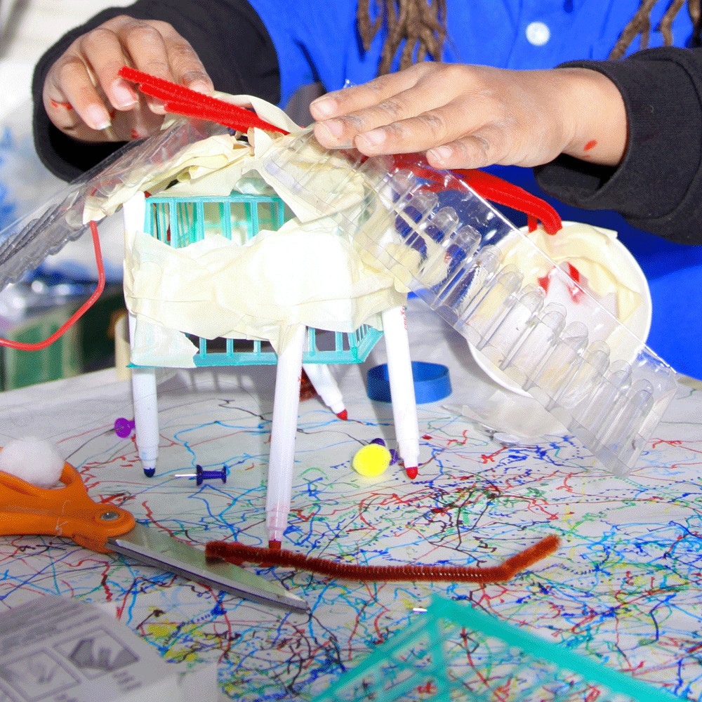 An up close image of a child working on making an object out of various materials.