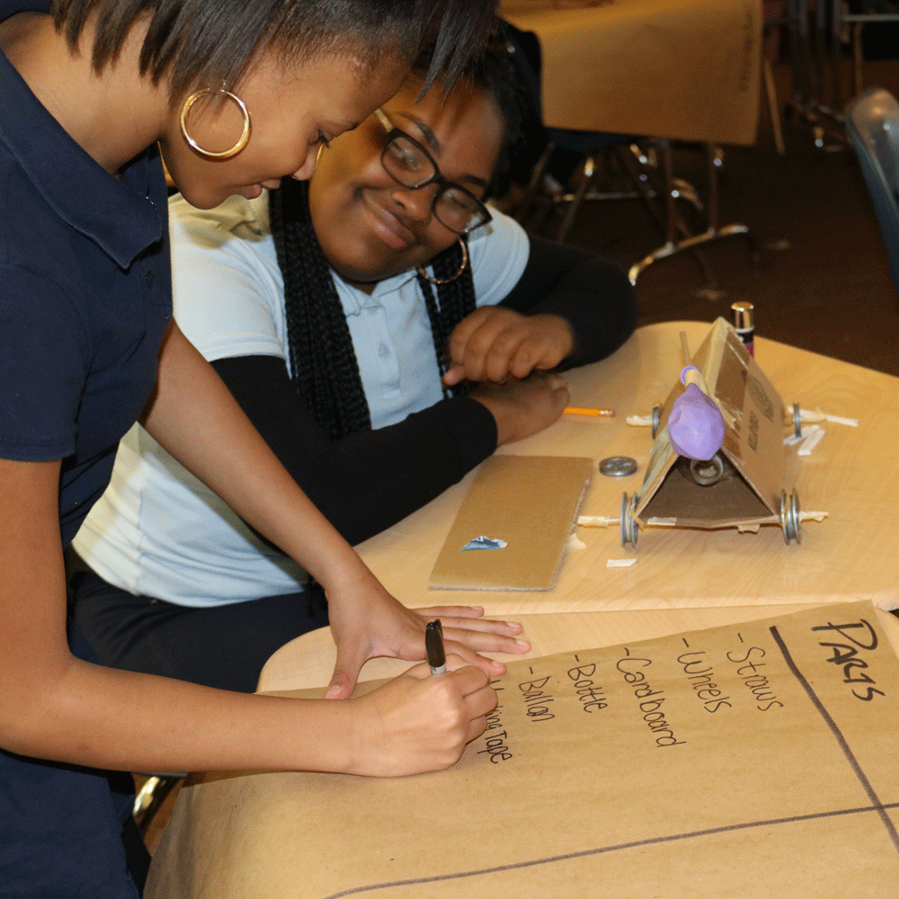 Students writing a list on a large piece of construction paper.