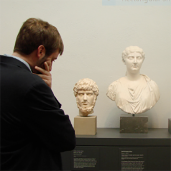 Museum Image of a man standing in front of two sculptures